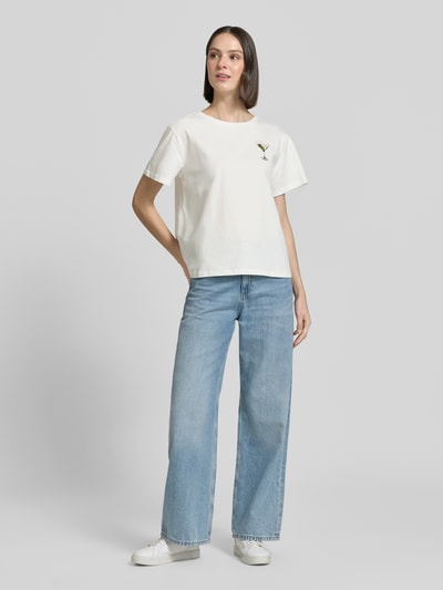 Frauenmodel trägt Damen T-Shirt mit Label-Print Modell 'Eleanor' von LOLLYS LAUNDRY aus Reiner Baumwolle, Regular-Fit, Rundhalsausschnitt, Farbe Weiß, kombinierbar zu Jeans, Rückenlänge bei Größe S 57 cm, Ganzkörperansicht von vorne.
