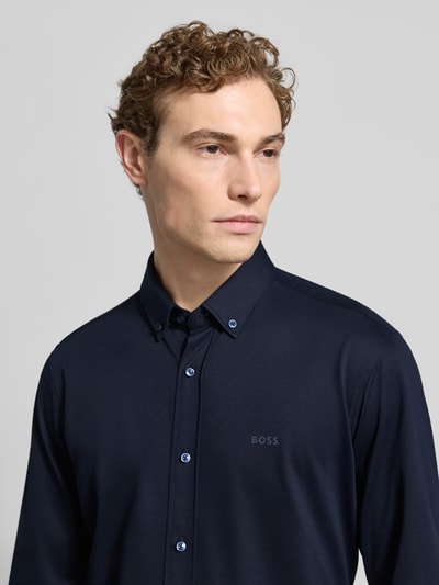 Männermodel trägt Regular Fit Businesshemd aus Pinpoint mit Stretch-Anteil von BOSS, dunkelblau, Baumwoll-Mix, Nahaufnahme Oberkörper, Logo-Schriftzug, Button-Down-Kragen, Knopfleiste, Sportmanschetten, pflegeleicht, atmungsaktiv, schnell trocknend