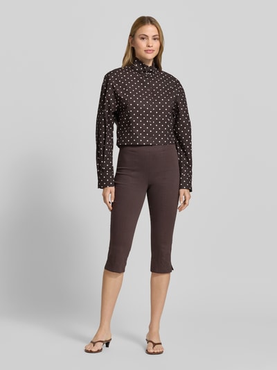 Frauenmodel trägt Kurze voluminöse Bluse - curated by Mary Braun von Style Icon Collection, reine Baumwolle, schwarz mit weißen Punkten, Regular Fit, Stehkragen, durchgängige Knopfleiste, Ganzkörperansicht von vorne.