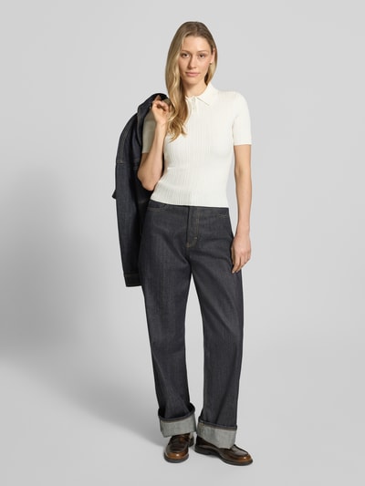 Frauenmodel trägt Slim Fit Strickpullover aus Viskose-Mix Modell 'Sareplette' von HUGO, Strickoptik, Struktur-Muster, Polokragen, V-Ausschnitt, Kurzarm, Materialverarbeitung Strick, Farbe creme, Ganzkörperansicht von vorne.