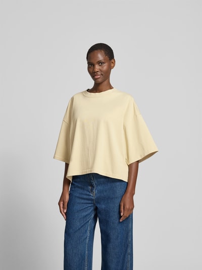 Frauenmodel trägt T-Shirt mit Rundhalsausschnitt von black palms in Beige, Relaxed-Fit aus reiner Baumwolle, Halbarm, vorne Ganzkörperansicht. Rückenlänge 55 cm bei Größe S.