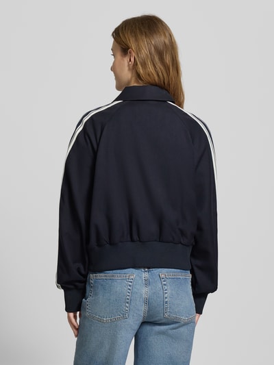 Frauenmodel trägt Regular Fit Sweatjacke mit Viskose-Anteil von Marc O'Polo Denim in Dunkelblau, Kontraststreifen, gerippte Abschlüsse, Ganzkörperansicht Rückansicht.