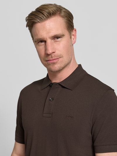Männermodel trägt Regular Fit Poloshirt aus reiner Baumwolle Modell 'PALLAS' von BOSS, Optik: Unifarben, Label-Stitching-Applikation, Polokragen, kurze Knopfleiste, Kurzarm, Bündchen: Gerippt, Materialverarbeitung: Piqué, Ganzkörperansicht von vorne.