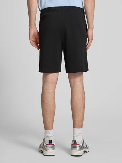 Männermodel trägt Shorts mit Label-Stitching mit elastischem Bund von CHAMPION in Schwarz, Baumwoll-Mix, Regular Fit, Ganzkörperansicht Rückansicht.