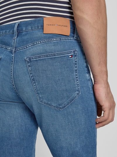 Männermodel trägt Regular Fit Jeans aus Baumwoll-Mix von Tommy Hilfiger, stylizowana na denim, krój regular fit, naszywka z logo, nity, wyhaftowane logo, szlufki na pasek, zapięcie na guzik i zamek błyskawiczny, 5 kieszeni, mieszanka bawełny, detailaufnahme tylniej kieszeni