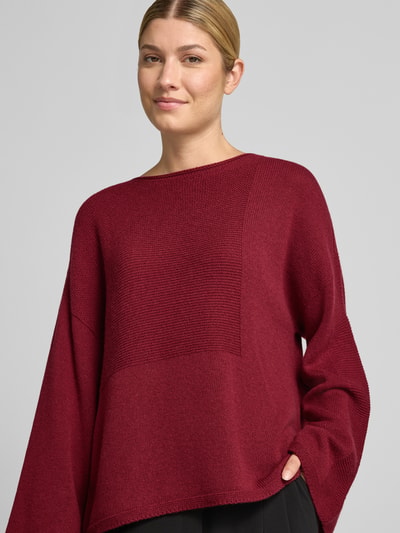 Frauenmodel trägt Oversized Pullover aus reiner Baumwolle in Strick-Optik von Emporio Armani in Dunkelrot, Strukturmix, Ganzkörperansicht von vorne.