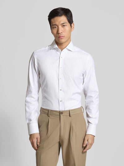 Männermodel trägt Slim Fit Business-Hemd mit Kentkragen von ETERNA aus reiner Baumwolle, langärmelig, Knopfleiste, Sportmanschetten, Ganzkörperansicht von vorne.