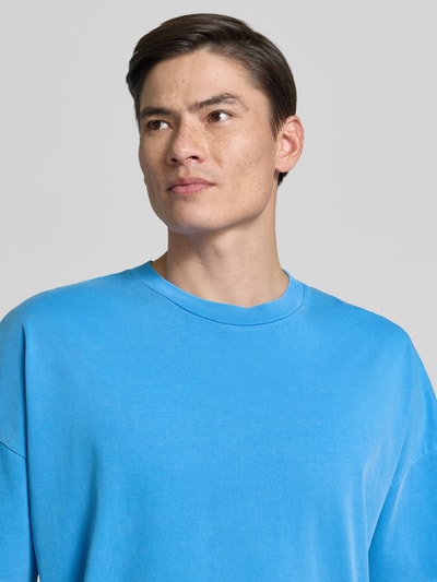 Männermodel trägt T-Shirt mit geripptem Rundhalsausschnitt Modell 'FIZVALLEY' von American Vintage in Blau, Reine Baumwolle, Loose-Fit, Nahaufnahme Oberkörper. Rückenlänge bei Größe M/L 72 cm.