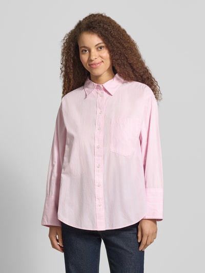 Frauenmodel trägt Regular Fit Bluse mit Brusttasche von Gina Tricot, Reine Baumwolle, Hemdblusenkragen, Knopfleiste, Brusttasche, Rückenlänge 71 cm, Ärmellänge 55 cm, rosa Farbton, weiche Textur, Ganzkörperansicht von vorne.