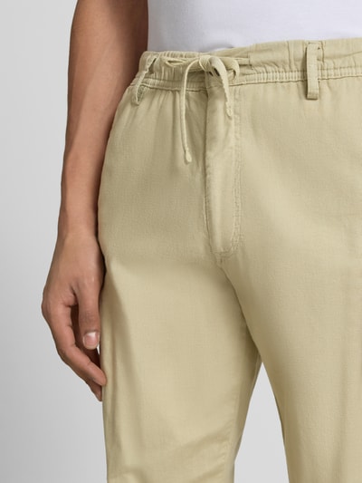 Männermodel trägt Relaxed Fit Hose aus Baumwoll-Leinen-Mix Modell 'KANE' von Jack & Jones in Beige mit elastischem Bund und Schnürung, Nahaufnahme Oberkörper. Bundweite bei Größe M: 42 cm, Innenbeinlänge: 82 cm, Gesäßtaschen, natürliche Struktur.