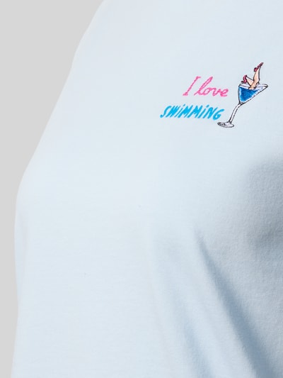 Frauenmodel trägt Damen T-Shirt mit Rundhalsausschnitt aus reiner Baumwolle, Motiv- und Statement-Stitching, Modell 'EMILIE' von MC2 Saint Barth, Nahaufnahme Oberkörper.