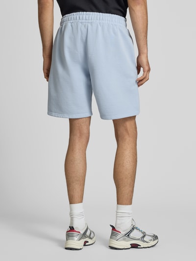 Männermodel trägt Regular Fit Shorts mit Logo-Stitching von Pegador aus Baumwoll-Mix in Hellblau, elastischer Bund, Ganzkörperansicht Rückansicht.