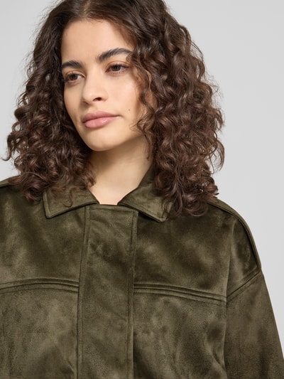 Frauenmodel trägt Regular Fit Blouson in Wildlederoptik Modell 'AMBER' von Only in Olivgrün mit Umlegekragen, Nahaufnahme Oberkörper.
