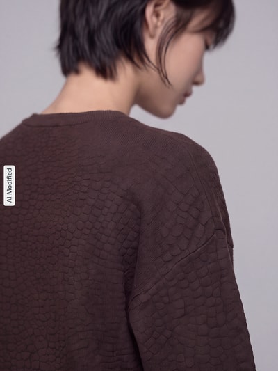 Frauenmodel trägt Regular Fit Pullover aus Viskose-Mix Modell 'NANCY' von VERO MODA, braune Farbe, Strukturmuster, Nahaufnahme Rückansicht, KI-modifiziertes Bild.