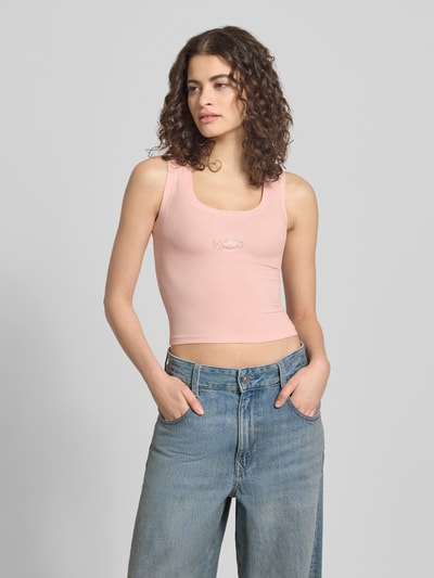 Frauenmodel trägt Slim Fit Top mit Logo-Detail von ANOTHER COTTON LAB aus elastischem Baumwoll-Mix in Rosa, Rundhalsausschnitt, Nahaufnahme Oberkörper. Rückenlänge bei Größe S: 37 cm.