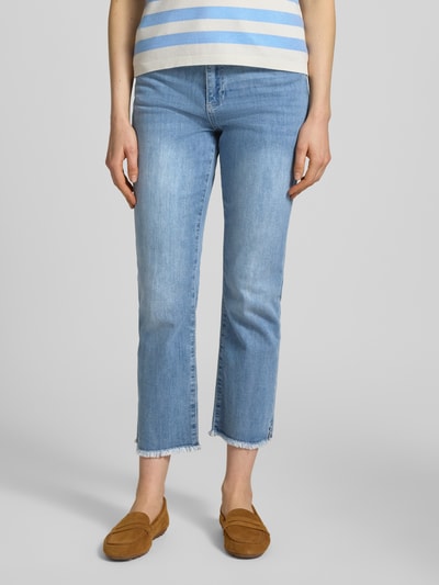 Kobieta nosi Cropped Jeans mit Fransen von More & More, mieszanka bawełny i elastanu, wpuszczane kieszenie, frędzle, skrócony krój, jasnoniebieski denim, Szerokość w rozmiarze 36: 40 cm, długość wewnętrzna nogawki w rozmiarze 36: 65 cm, Ganzkörperansicht z przodu.