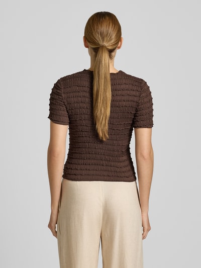 Kobieta modelka nosi T-Shirt mit Strukturmuster und Rundhalsausschnitt od Jake*s Collection, materiał z domieszką stretchu, krój slim fit, wzór strukturalny w kolorze brązowym, długość tyłu w rozmiarze S: 48 cm, widok całej sylwetki z tyłu.