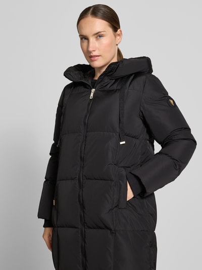 Frauenmodel trägt Regular Fit Mantel in Stepp-Optik Modell 'Nova' von MOS MOSH in Schwarz, mit Kapuze und Zweiwege-Reißverschluss, Nahaufnahme Oberkörper. Rückenlänge 102 cm, Schulterbreite 42 cm, Brustweite 46 cm, Ärmellänge 64 cm.