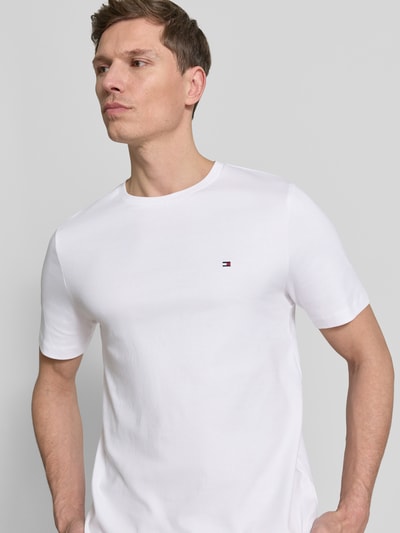 Männermodel trägt Regular Fit T-Shirt aus reiner Baumwolle von Tommy Hilfiger, unifarben weiß, Rundhals, Logo-Detail, Nahaufnahme Oberkörper