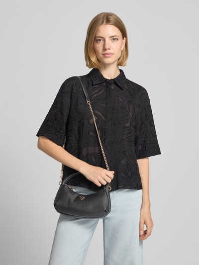 Frauenmodel trägt Mini Hobo Bag in Leder-Optik Modell 'GILDA' von GUESS mit Strukturmuster und Brand-Applikation, Nahaufnahme Oberkörper.