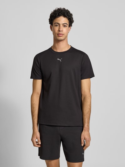 Männermodel trägt Regular Fit T-Shirt mit Rundhalsausschnitt von PUMA PERFORMANCE aus Baumwoll-Viskose-Mix, Logo-Print, schwarze Farbe, Ganzkörperansicht von vorne. Rückenlänge bei Größe S: 51 cm, Ärmellänge bei Größe S: 70 cm.
