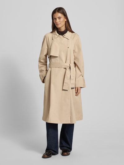 Frauenmodel trägt Mantel mit Logo-Detail von Emporio Armani in Beige, Material-Mix mit Baumwoll-Anteil, taillierte Passform, ausgestellte Passform, Umlegekragen mit Ziersteinbesatz, abnehmbares Taillenband, Doppelknopfleiste, Rückenlänge 108 cm, Schulterbreite 41 cm, Brustweite 53 cm, Ärmellänge 62 cm, Ganzkörperansicht von vorne.