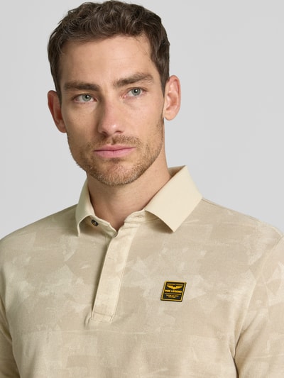 Męskimodel nosi Slim Fit Poloshirt mit Label-Patch od PME Legend z bawełny, wzór na całej powierzchni, listwa guzikowa, z naszywką z logo, krój slim fit, długość tyłu w rozmiarze M: 74 cm, jasny beż, prosty materiał, zbliżenie na górną część ciała, przód.