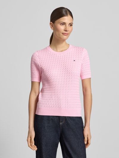 Frauenmodel trägt Slim Fit T-Shirt aus reiner Baumwolle von Tommy Hilfiger in Optik: Unifarben mit Zopfmuster, Logo-Detail, Strick, Ganzkörperansicht von vorne.