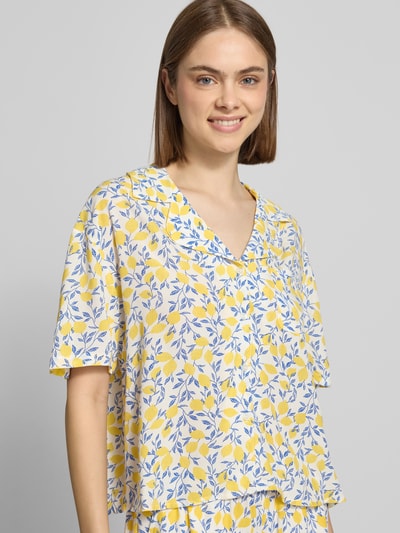 Frauenmodel trägt Relaxed Fit Hemdbluse aus reiner Viskose Modell 'BARRI' von Pieces mit floralem Allover-Muster in Gelb und Blau, Nahaufnahme Oberkörper.