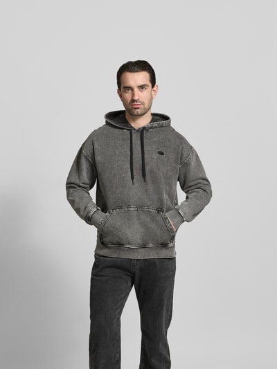 Männermodel trägt Relaxed Fit Hoodie in Denim-Optik von Diesel aus reiner Baumwolle mit Kapuze, Tunnelzug, Logo-Stitching, Ganzkörperansicht von vorne.