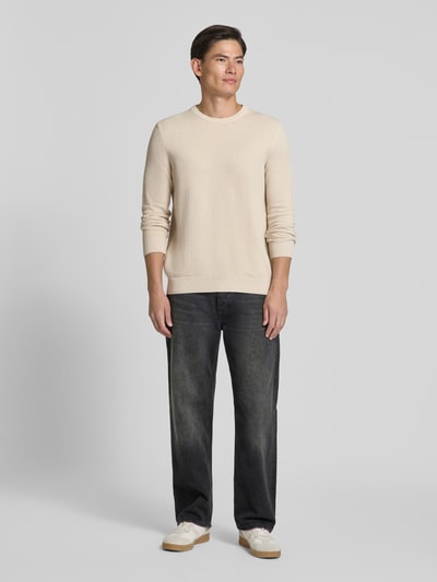 Męski model nosi Regular Fit Pullover aus reiner Baumwolle von Marc O'Polo, jasnobeżowy sweter z bawełny, ciemne dżinsy, białe buty, całopostaciowy widok z przodu.