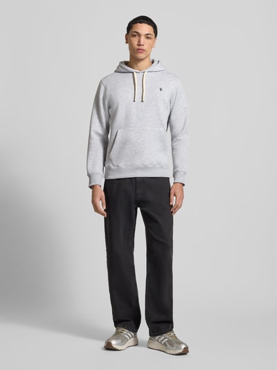 Mannelijk model draagt Slim Fit Hoodie met logo-stitching van REVIEW, katoenmix, kangoeroezak, capuchon met tunnelkoord, elastische boorden, slim fit, ruglengte 66 cm, mouwlengte 63 cm, grijs met zwarte broek, neutrale achtergrond, kleuren en texturen goed zichtbaar. Ganzkörperansicht von voren.