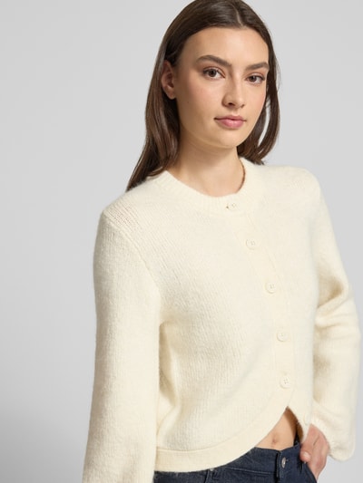 Frauenmodel trägt Strickjacke mit Rundhalsausschnitt Modell 'Ally' von Gina Tricot, cremefarben, softer Alpaka-Materialmix, Nahaufnahme Oberkörper.
