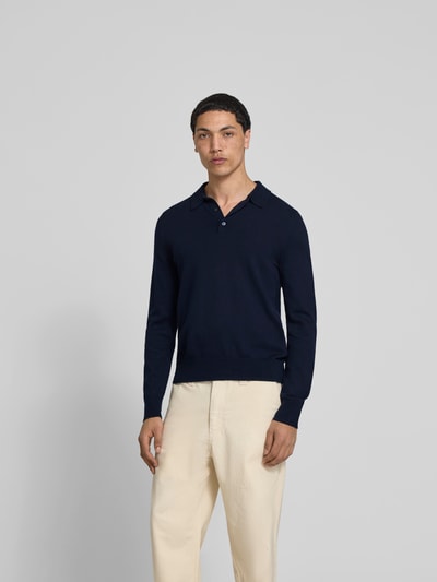Männermodel trägt Slim Fit Poloshirt aus Woll-Mix von Filippa K in Dunkelblau, Strick-Optik, langärmelig, elastische Abschlüsse, Ganzkörperansicht von vorne. Rückenlänge bei Größe M: 67 cm.