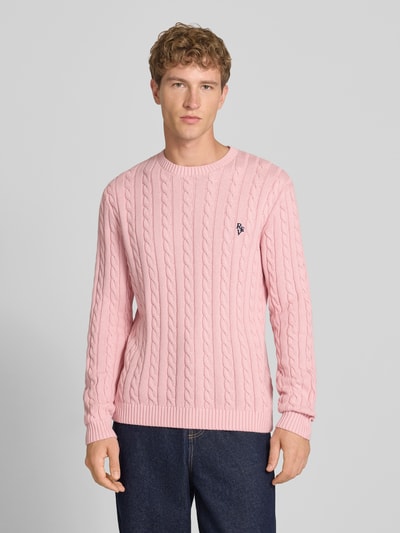 Männermodel trägt Slim Fit Strickpullover reine Baumwolle von REVIEW, rosa Zopfmuster, Logo Stickerei, Nahaufnahme Oberkörper.
