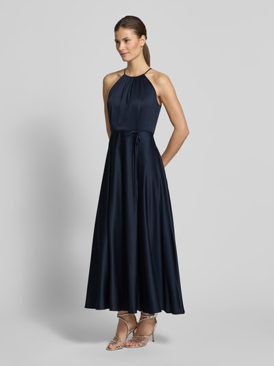 Frauenmodel trägt Cocktailkleid aus Satin mit Bindegürtel von Jake*s Cocktail in Dunkelblau, A-Linie, Neckholder, Ganzkörperansicht von vorne.