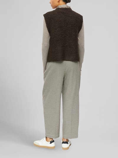 Frauenmodel trägt Regular Fit Strickweste mit Woll-Anteil von s.Oliver RED LABEL in Dunkelbraun, kombiniert mit heller Hose, Ganzkörperansicht Rückansicht.