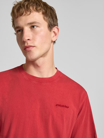 Mannelijk model draagt T-shirt met Rundhalsausschnitt und Label-Stitching van Dickies in rood, pure katoen, regular fit, nahaufnahme bovenlichaam.