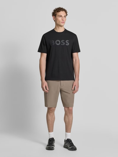 Mannenmodel draagt Slim Fit Chinoshorts met persplooien van BOSS Green in lichtbruin, gladde textuur, Ganzkörperansicht van voren.