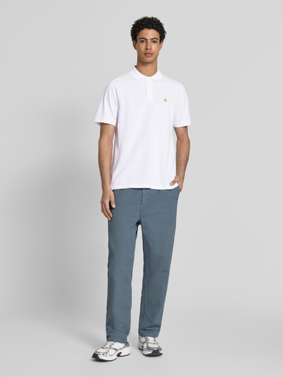 Männermodel trägt Regular Fit Poloshirt mit Label-Stitching von Carhartt Work In Progress aus Reine Baumwolle, Ganzkörperansicht von vorne.