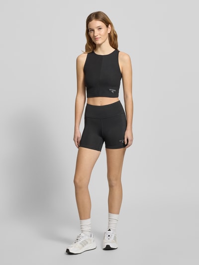 Frauenmodel trägt schwarzes PUMA x HYROX - Crop Top mit Label-Stitching, Slim Fit, Rundhalsausschnitt, Baumwoll-Mix mit Stretch, Ganzkörperansicht von vorne.