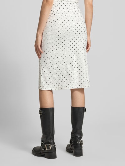 Frauenmodel trägt Midirock im Allover-Look Modell '90s von Gina Tricot aus Material-Mix mit Stretch-Anteil in Weiß mit schwarzen Punkten, figurbetonter Schnitt, Damen, Bundweite 36 cm, Gesamtlänge 62 cm, Ganzkörperansicht Rückansicht.