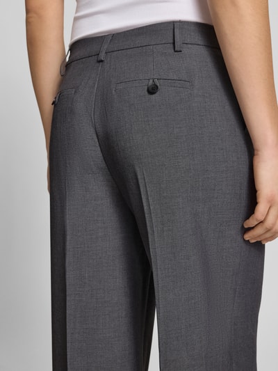 Frauenmodel trägt Wide Fit Stoffhose mit Viskose-Anteil von Gina Tricot in Grau mit Gesäßtaschen und Bügelfalten, Nahaufnahme Rückansicht.