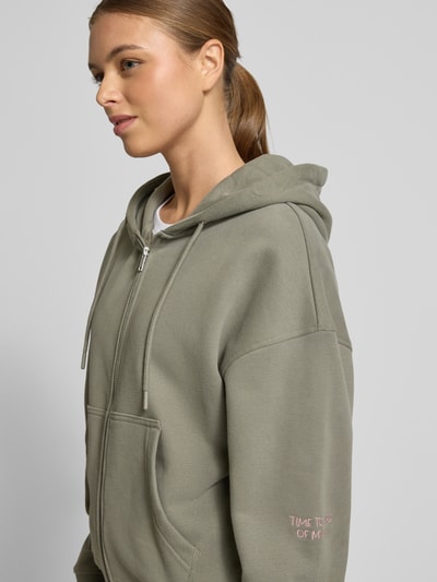 Frauenmodel trägt Oversized Sweatjacke mit Kapuze von Smith and Soul aus Baumwoll-Mix, Tunnelzug, Reißverschluss, Eingrifftaschen, gerippte Abschlüsse, Ganzkörperansicht von vorne.
