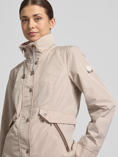 Frauenmodel trägt Regular Fit Jacke mit Logo-Patch von Gil Bret in Beige, mit Stehkragen, Reißverschlusstaschen, Nahaufnahme Oberkörper.