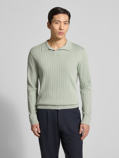 Męski model nosi Loose Fit Poloshirt aus reiner Baumwolle Modell 'TORINO' od SELECTED HOMME, gładki wzór, długi rękaw, prążkowana struktura, jasna zieleń; zdjęcie całej sylwetki z przodu.