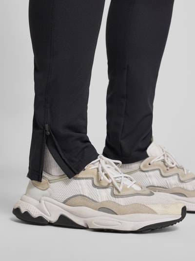 Männermodel draagt Trainingshose met ritszakken van Under Armour, regular fit, elastische band, detailopname onderbenen.