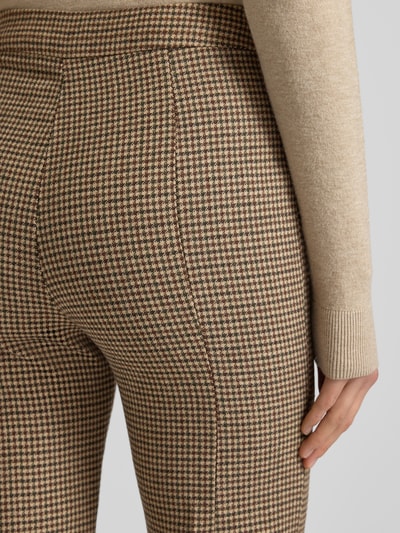 Frauenmodel trägt Flared Stoffhose mit Bundfalten Modell 'GINA' von Mango, kariertes Muster, Material-Mix mit Lanawoll-Anteil, Detailaufnahme.