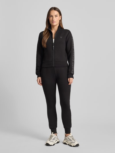 Frauenmodel trägt schwarze Sweatpants mit elastischem Bund Modell 'ALLIE' von Guess Activewear, lockerer Schnitt, Ganzkörperansicht von vorne.