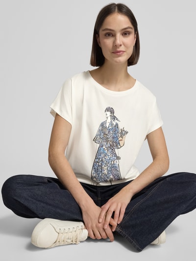 Frauenmodel trägt Damen T-Shirt mit Motiv-Print von Oui aus Baumwoll-Mix mit Modal-Anteil, Rundhalsausschnitt, Relaxed-Fit, Ziersteinbesatz, Rückenlänge 59 cm, Ganzkörperansicht von vorne.
